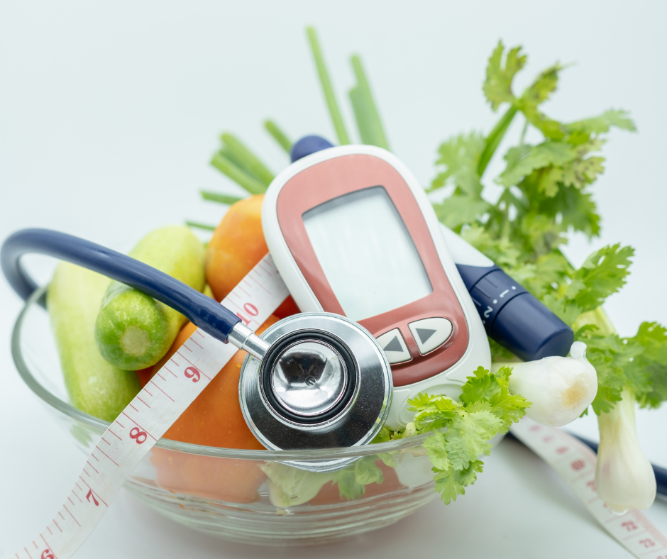 A bowl filled with fresh vegetables like carrots, cucumbers, and herbs, accompanied by a stethoscope, blood glucose monitor, and measuring tape, symbolizing healthy living and weight management.